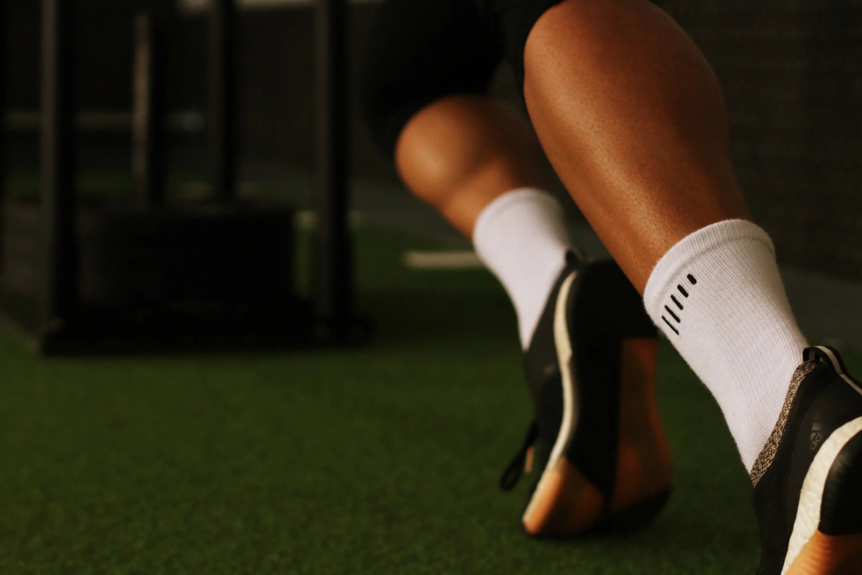 Person wearing white socks and black shoes on a grassy field